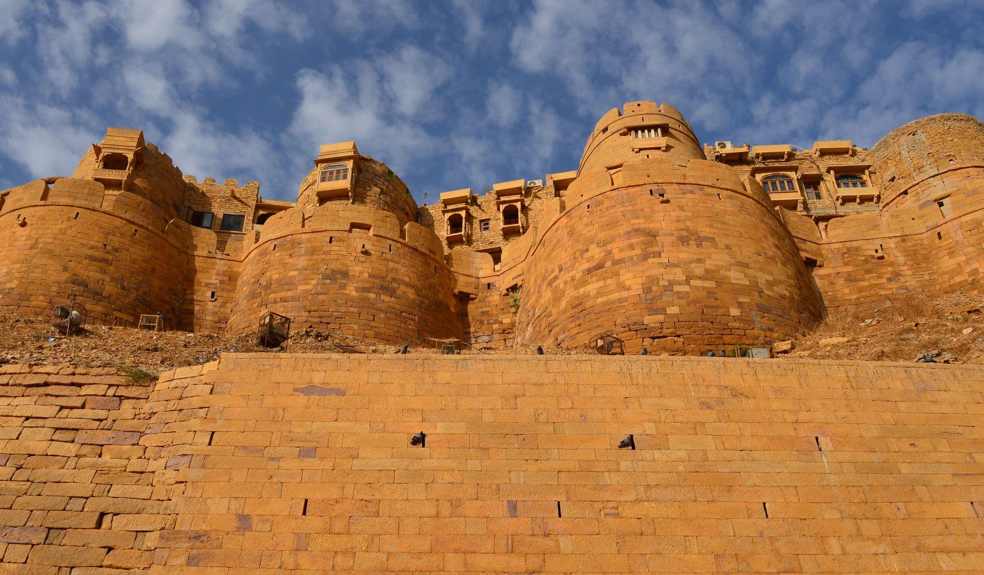 Golden sandstone bastions of Jaisalmer Fort rising above a stone rampart